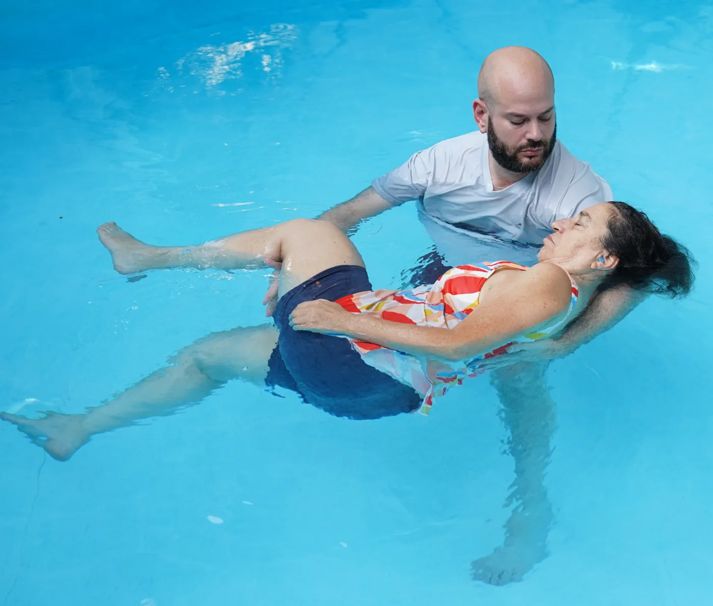 ליווי תנועה עדינה במים — מטפל מנחה גוף צף בסיבוב רך בבריכה