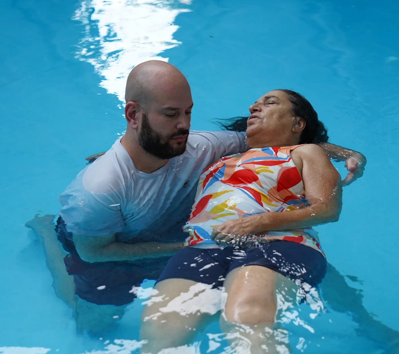 מטפל מחזיק ותומך במטופלת הצפה על גבה במים חמימים במהלך טיפול אישי