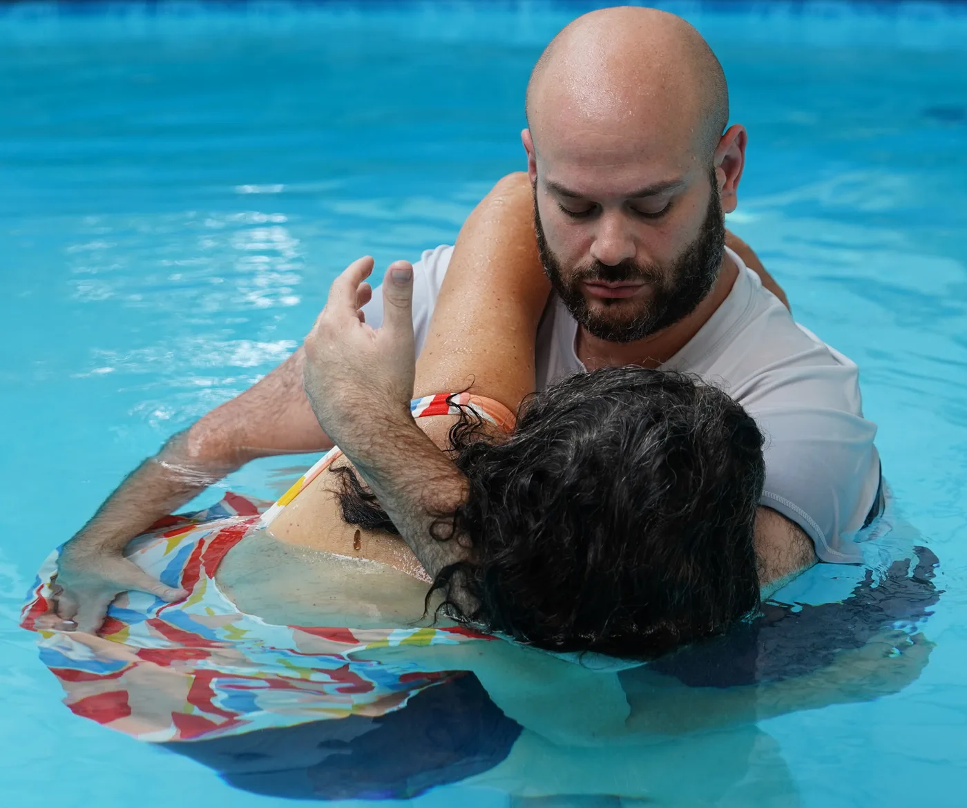 המטפל מחזיק את המטופלת בחיבוק תומך במים במהלך מפגש טיפולי